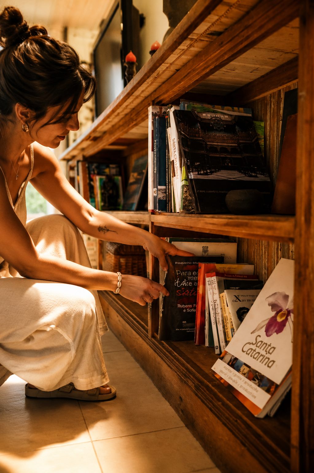 Hóspede consultando um dos livros sobre arte e cultura de Santa Catarina, na biblioteca curada da Lagoa Nômade